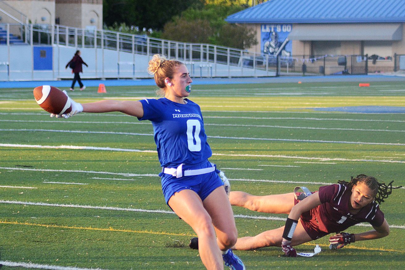 Marymount’s Samantha Bulik stretches the ball across the pylon while having her flagged pulled by Eastern’s Damiyae Moyet in the Atlantic East Championship for women’s flag football on Saturday, April 26, 2025, in Arlington, Va.